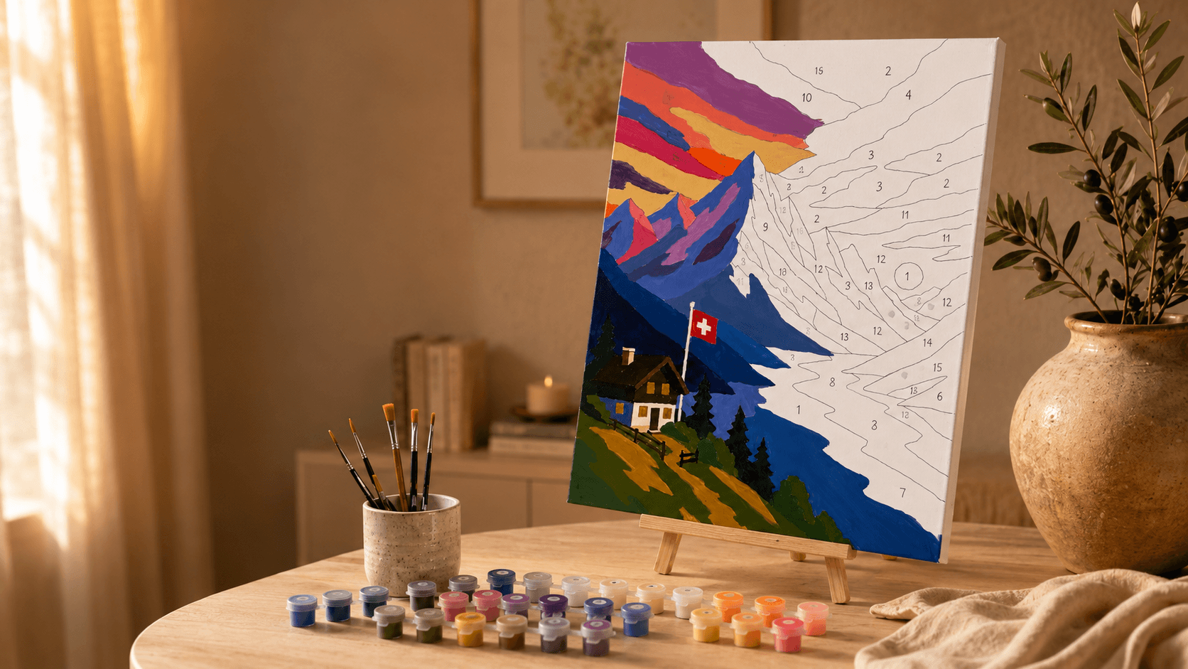 Partially painted Swiss mountain paint-by-numbers canvas on an easel with paint pots and brushes